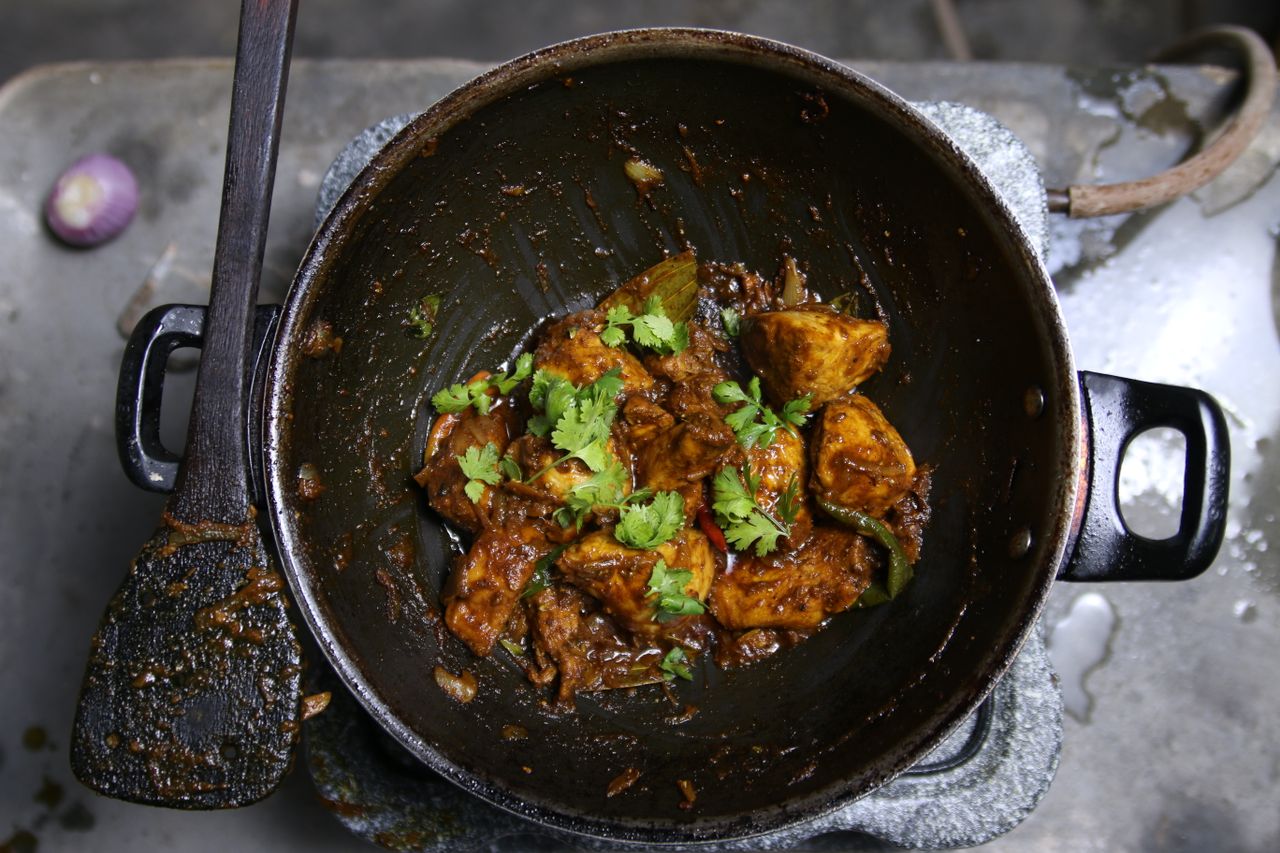 Delicious Indian curry with herbs, cooked in a traditional wok. Perfect for food lovers.