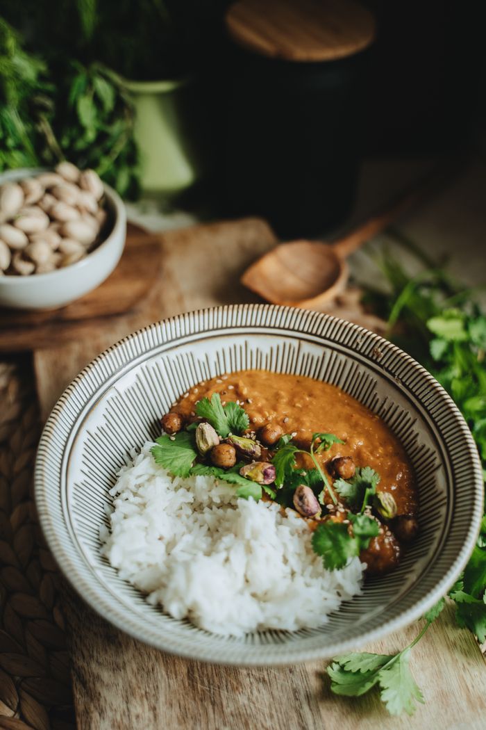 Services A bowl of vegan lentil curry with rice garnished with cilantro, perfect for a healthy meal.